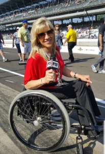 Maria in wheelchair holding microphone at racetrack