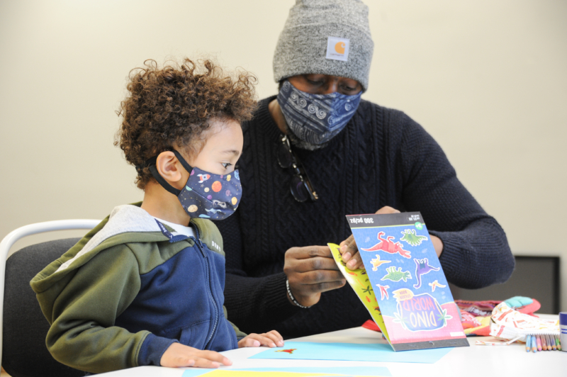 Kid and adult working on a sticker project while wearing masks