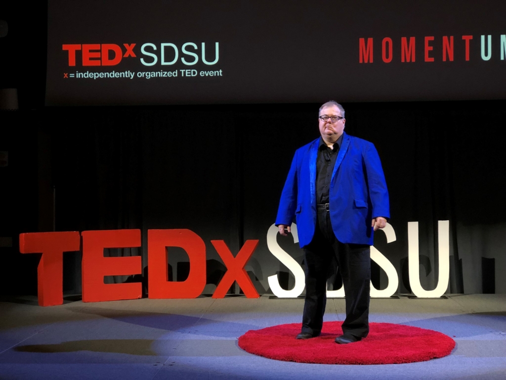 John Kippen stands onstage a TEDx event at San Diego State University